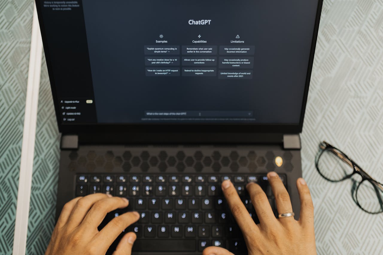 Hands typing on a laptop with ChatGPT open, wireless technology theme.